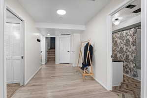 Hallway with light wood-style flooring and recessed lighting
