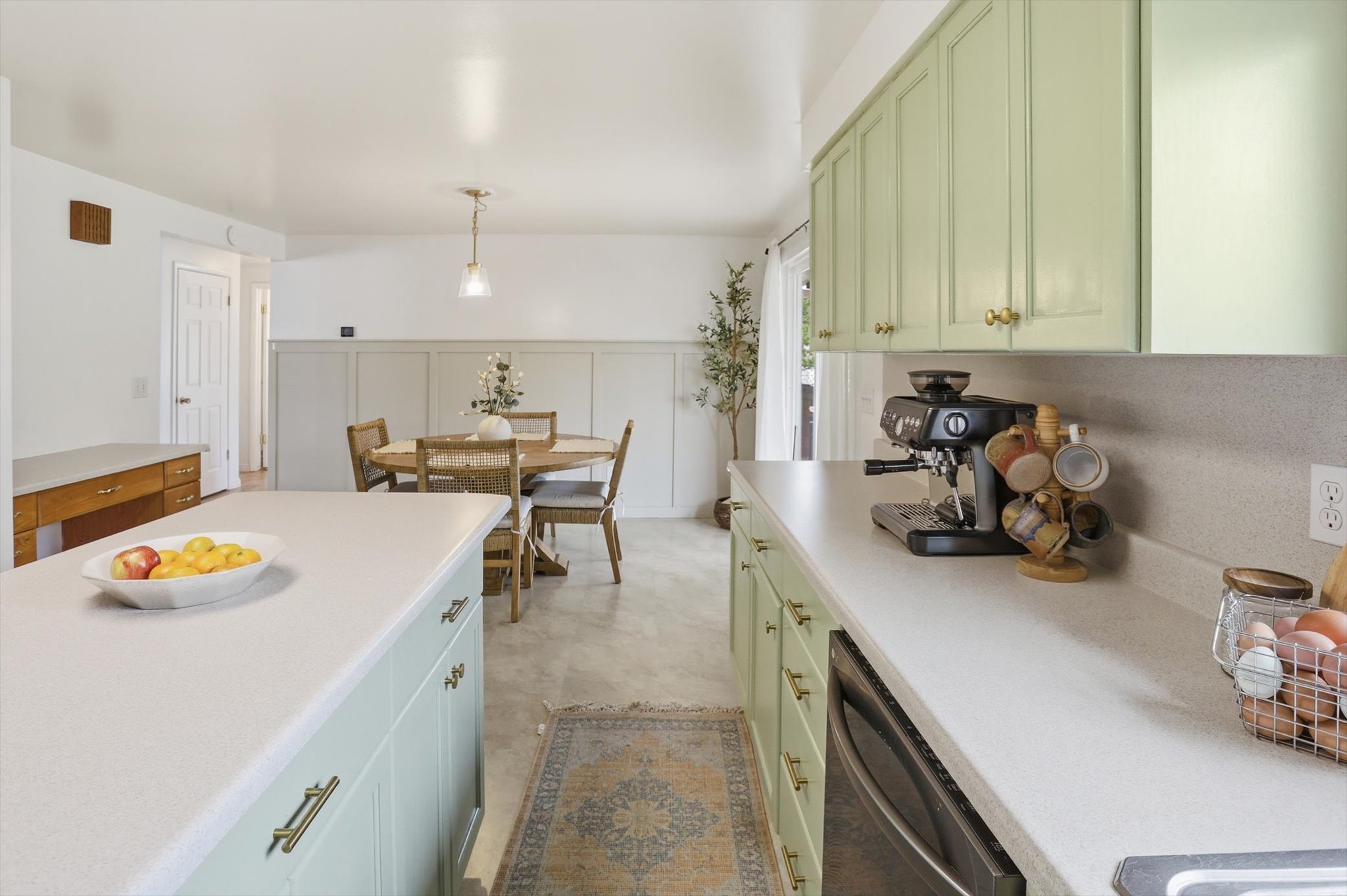 Kitchen featuring green cabinetry, dishwasher, light countertops, and hanging light fixtures