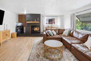 Living room with light wood-type flooring, a fireplace, and a textured ceiling