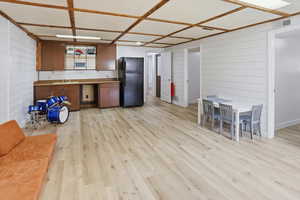 Kitchen featuring freestanding refrigerator, light wood-type flooring, wooden walls, and wood finish cabinetry
