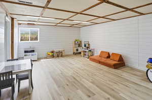 Rec room featuring light wood-type flooring and wooden walls