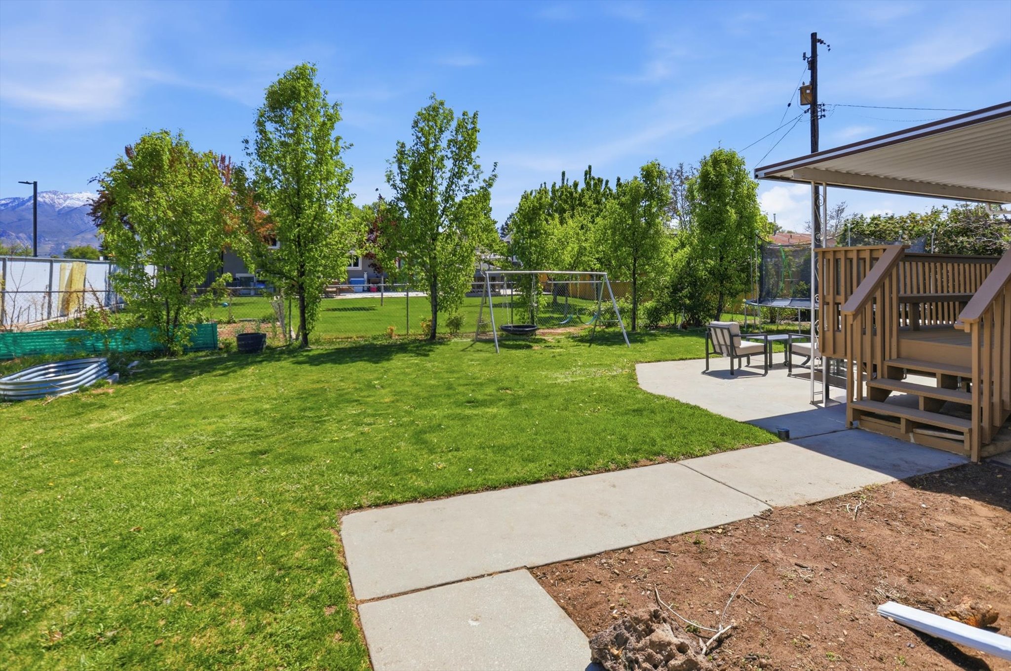 Fenced backyard with a trampoline, a playground, and a patio