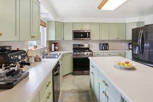 Kitchen featuring green cabinets, stainless steel appliances, and light countertops