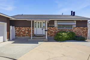 View of front of home with brick siding, a shingled roof, a garage, and concrete driveway