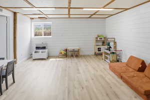 Living area featuring light wood-style flooring, wooden walls, and heating unit