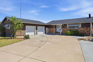 Ranch-style house with roof with shingles, a garage, driveway, and brick siding