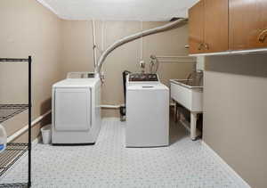 Laundry area with washer and dryer, light floors, and cabinet space