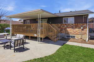 Rear view of property featuring outdoor lounge area, brick siding, a deck, and roof with shingles