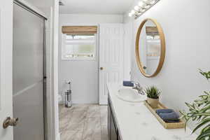 Full bathroom featuring vanity, a stall shower, and light marble finish flooring
