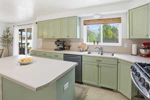 Kitchen featuring green cabinetry, stainless steel appliances, light countertops, and a kitchen island