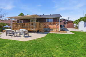 Back of property with a patio area, an outdoor hangout area, brick siding, a lawn, and a shed