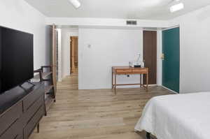 Bedroom with light wood-type flooring and a textured ceiling