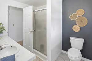 Full bathroom featuring double vanity, a stall shower, and light marble finish floors