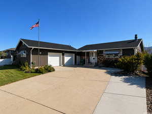 Single story home featuring driveway, a garage, and roof with shingles