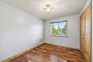 Cozy bedroom featuring hardwood flooring, natural light, and closet storage.