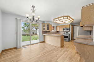 Open kitchen and dining space with ample cabinetry, breakfast bar seating, and sliding glass doors leading to the backyard.
