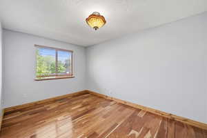 Bright secondary bedroom with hardwood flooring and natural light.