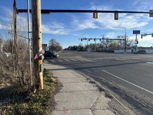 View of asphalt street with traffic lights, sidewalks, traffic signs, and curbs