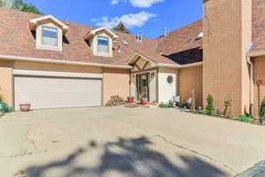 View of front of property with a shingled roof, driveway, and brick siding
