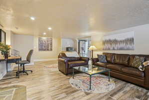 Living area featuring a textured ceiling, light wood-type flooring, and recessed lighting