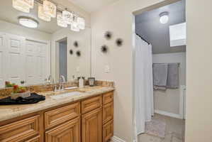 Bathroom with vanity, a shower with curtain, and light stone finish floors