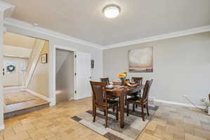 Dining space with crown molding, a textured ceiling, and stone tile flooring
