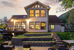 Back of house at dusk featuring stucco siding and a shingled roof