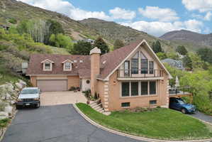View of front of home featuring brick siding, a chimney, a mountain view, and driveway