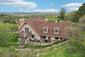 Rear view of property with a chimney, a patio area, roof with shingles, and a lawn