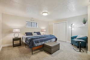 Carpeted bedroom featuring a textured ceiling and a closet