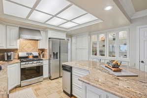 Kitchen featuring white cabinetry, stainless steel appliances, light stone countertops, crown molding, and recessed lighting