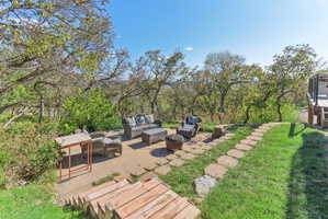 View of green lawn with a patio area and an outdoor living space with a fire pit