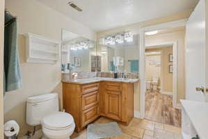 Bathroom with stone tile floors, vanity, and a textured ceiling