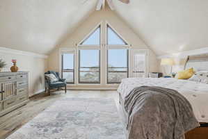 Bedroom with a textured ceiling, light wood-style floors, and a ceiling fan
