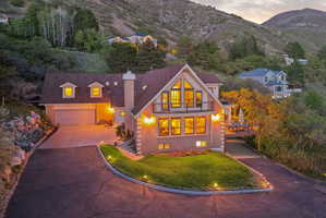 English style home featuring a balcony, brick siding, a chimney, driveway, and a mountain view