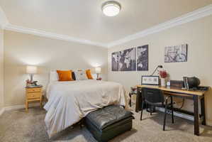 Bedroom with light carpet, ornamental molding, and an office area