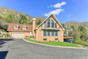 View of front facade with a mountain view, brick siding, a chimney, and asphalt driveway