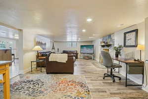 Living room with a textured ceiling, light wood-style floors, and recessed lighting