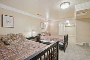 Bedroom with light carpet, a textured ceiling, and ornamental molding
