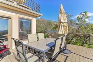 Wooden terrace with outdoor dining space, a mountain view, and grilling area