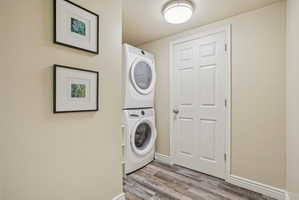Laundry area featuring stacked washer / dryer and light wood-style flooring