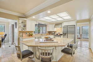Kitchen featuring stone tile floors, plenty of natural light, ornamental molding, recessed lighting, and white cabinets