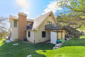 Back of house featuring stucco siding, a chimney, a yard, and roof with shingles