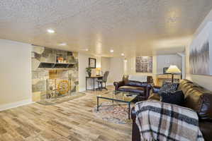 Living area featuring a textured ceiling, wood finished floors, a fireplace, and recessed lighting
