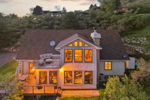 Back of property at dusk featuring a chimney and roof with shingles