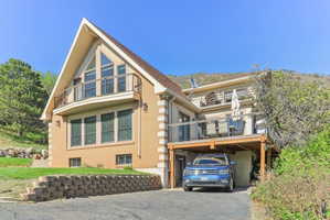 View of front of home featuring brick siding, a balcony, a carport, and asphalt driveway
