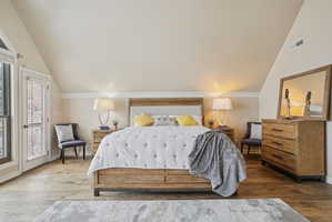 Bedroom with lofted ceiling, wood-type flooring, and access to outside
