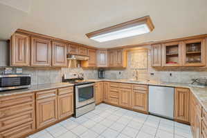 Kitchen featuring light stone counters, stainless steel appliances, and wood finish cabinetry