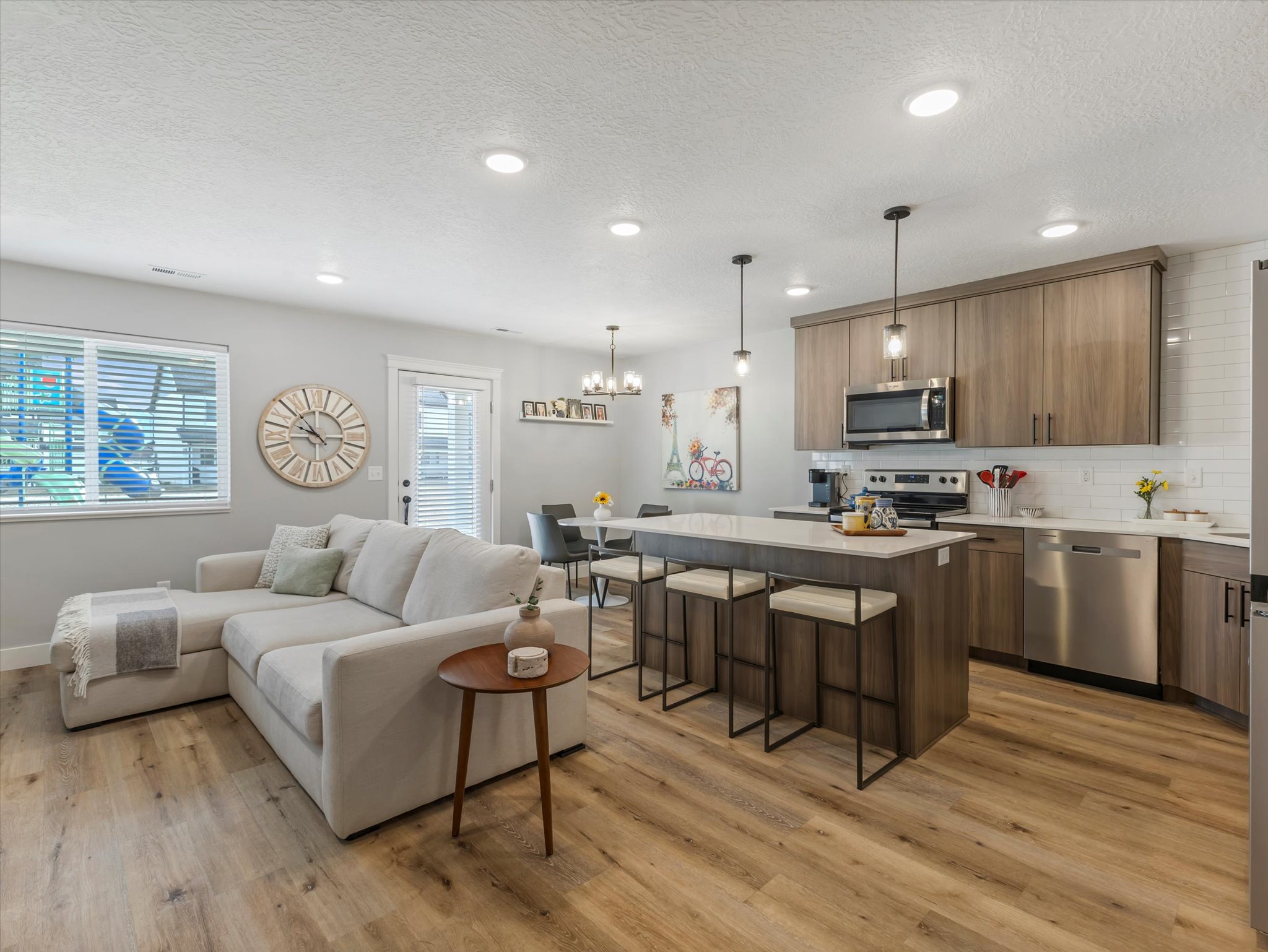 Living room with light wood finished floors, a textured ceiling, and hanging lights