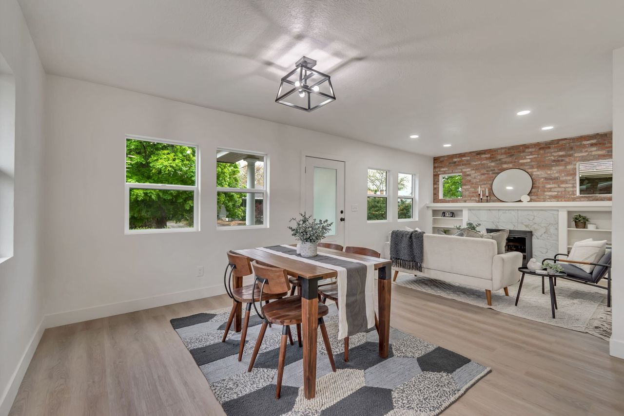 Dining space featuring a tiled fireplace, light wood-style floors, brick wall, and recessed lighting